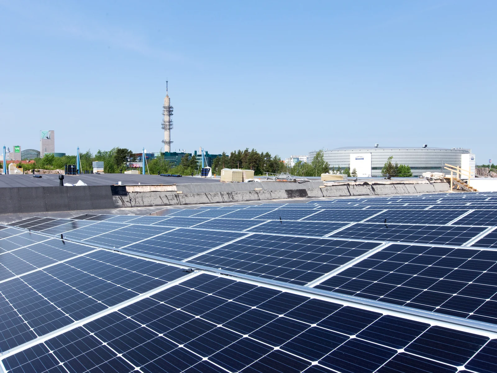 Grande installation photovoltaïque sur une toiture en ville, immeubles et tour en arrière-plan